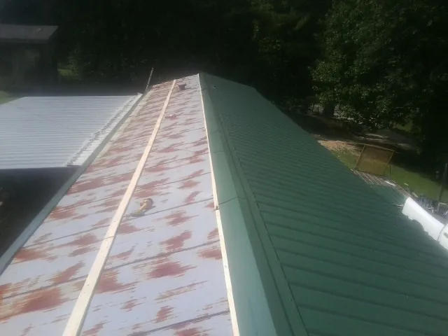 Old rusted panels beside newly installed green metal roofing — Wind Damage Roof Repair by Roofing Brothers in Indian Wells