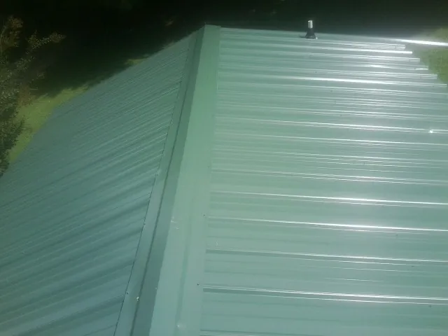 New green metal panels meeting at the ridge of a roof — Flat Roof Repair work by our crew in Indian Wells