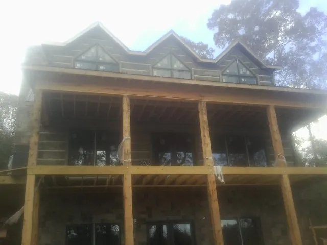 Dormers and porch framing on a large log home under construction — Roof Coating work by our crew in Indian Wells