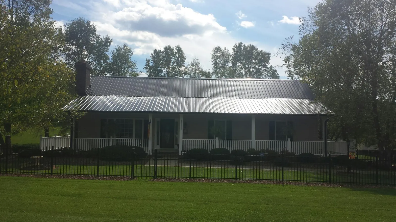 Gray metal roof on a brick ranch with a full width front porch — Gutter Guard Installation work by our crew in Indian Wells