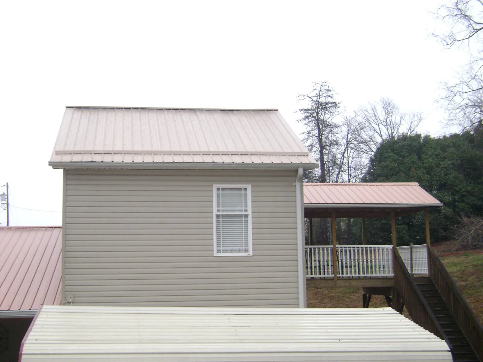 Tan metal roofs on a two story addition and attached porch, from a Roof Replacement job in Indian Wells