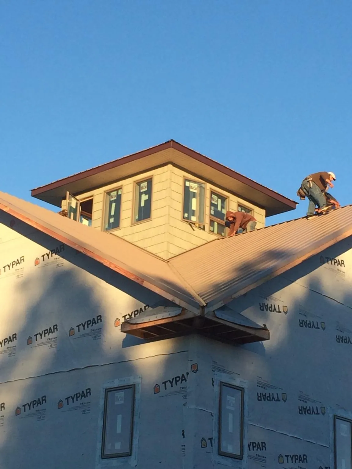 Roofers working around a rooftop cupola on a new metal roof at sunset — Roof Waterproofing in Indian Wells by Roofing Brothers